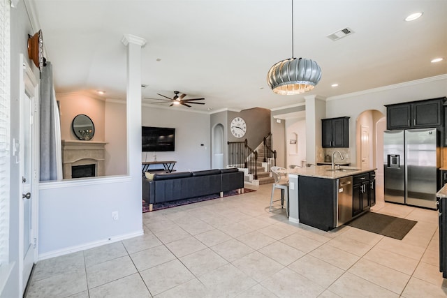 kitchen featuring visible vents, appliances with stainless steel finishes, arched walkways, a sink, and ornamental molding