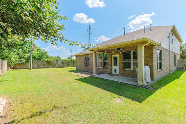 rear view of house with brick siding, a fenced backyard, a patio area, and a lawn