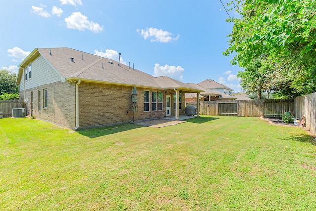rear view of house with a yard, brick siding, and a fenced backyard