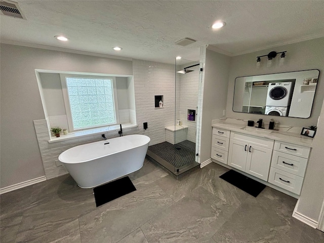 bathroom with visible vents, stacked washer and clothes dryer, a textured ceiling, a freestanding bath, and a shower stall