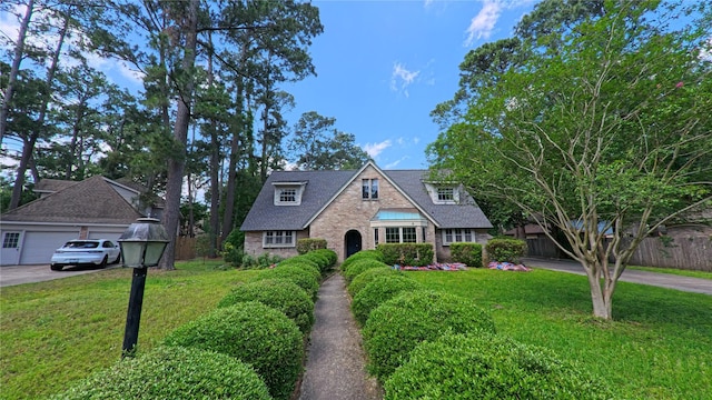 tudor-style house with brick siding, a front lawn, fence, and driveway