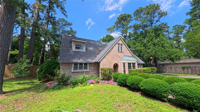 tudor house featuring fence, a front lawn, and brick siding