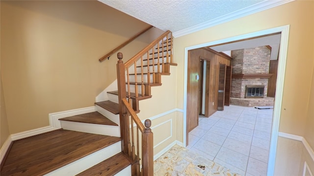 stairs featuring crown molding, a textured ceiling, tile patterned flooring, and a fireplace