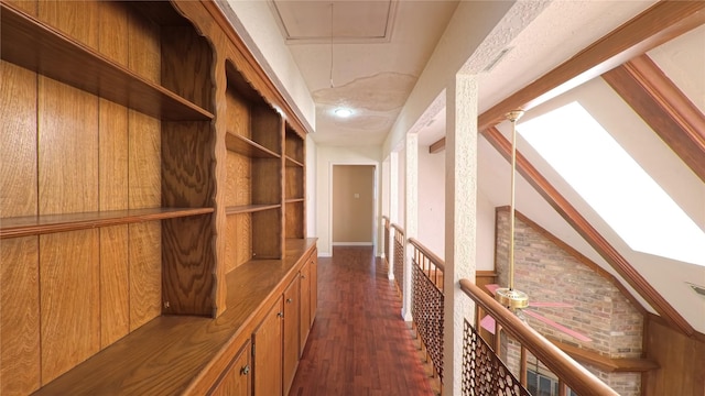 hall with an upstairs landing, lofted ceiling, attic access, and dark wood-type flooring
