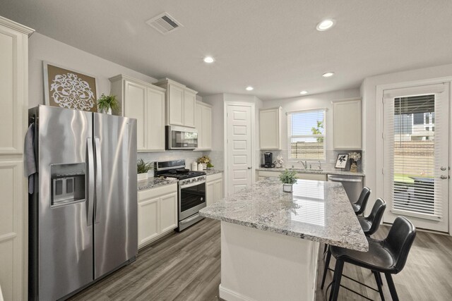 9904 Smokehouse Silo Ln, Houston, TX 77080 - kitchen featuring stainless steel appliances, wood finished floors, decorative backsplash, a sink, and recessed lighting