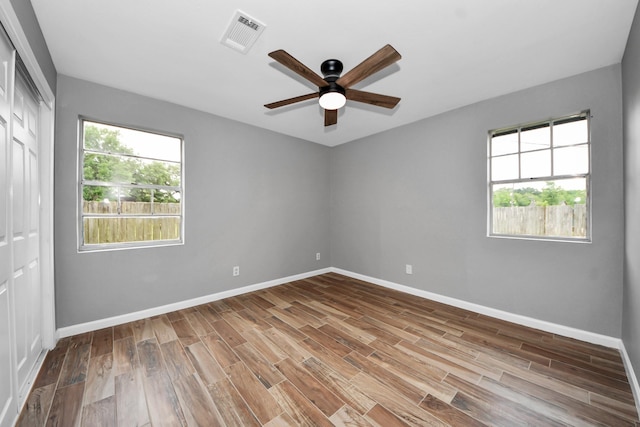 empty room featuring baseboards, ceiling fan, visible vents, and wood finished floors