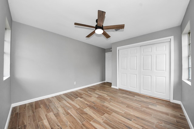 unfurnished bedroom with baseboards, ceiling fan, a closet, and light wood-type flooring