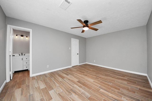 unfurnished bedroom with baseboards, a textured ceiling, light wood-style flooring, and visible vents