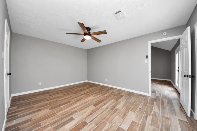 spare room featuring ceiling fan, a textured ceiling, visible vents, light wood-type flooring, and baseboards