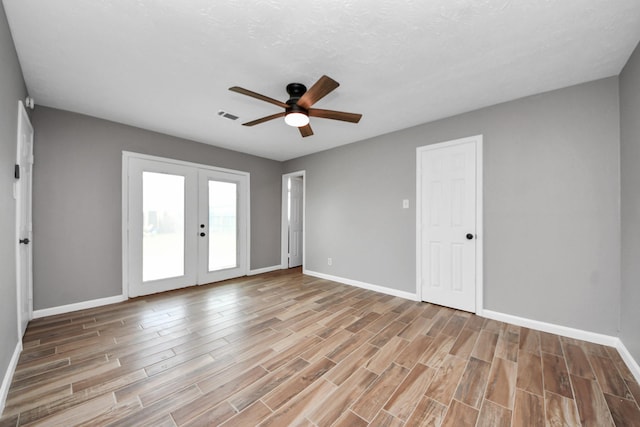 unfurnished room with visible vents, wood finished floors, baseboards, ceiling fan, and french doors