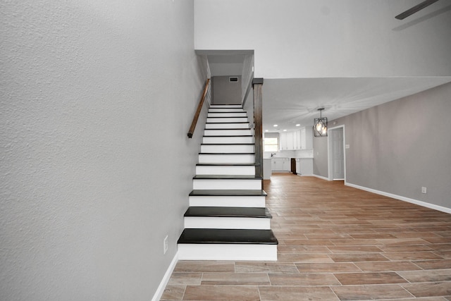 stairs featuring a ceiling fan, baseboards, and wood finished floors