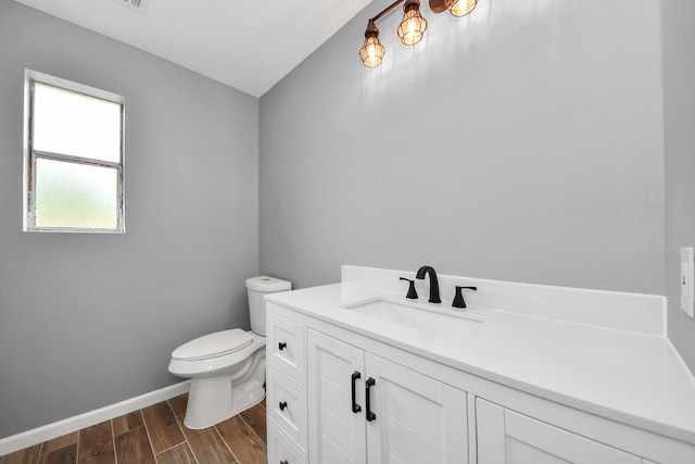half bathroom with toilet, baseboards, wood finished floors, and vanity