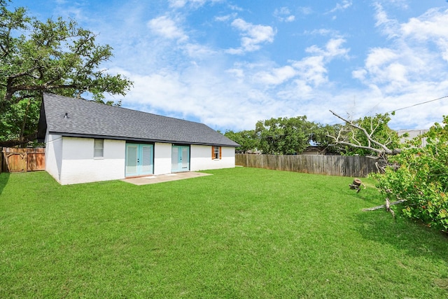 rear view of house with a fenced backyard, french doors, brick siding, a shingled roof, and a lawn