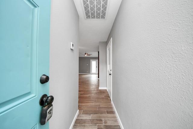 corridor featuring baseboards, wood finished floors, and visible vents