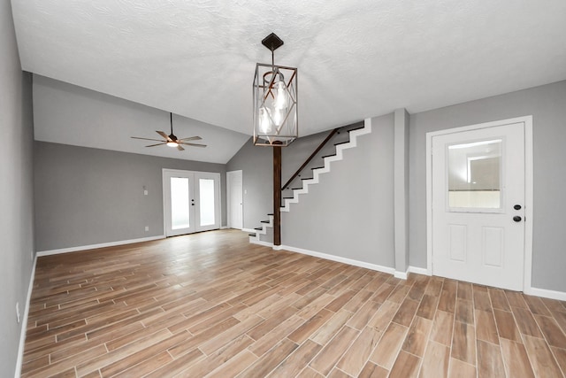 entrance foyer featuring ceiling fan, light wood finished floors, baseboards, lofted ceiling, and stairway