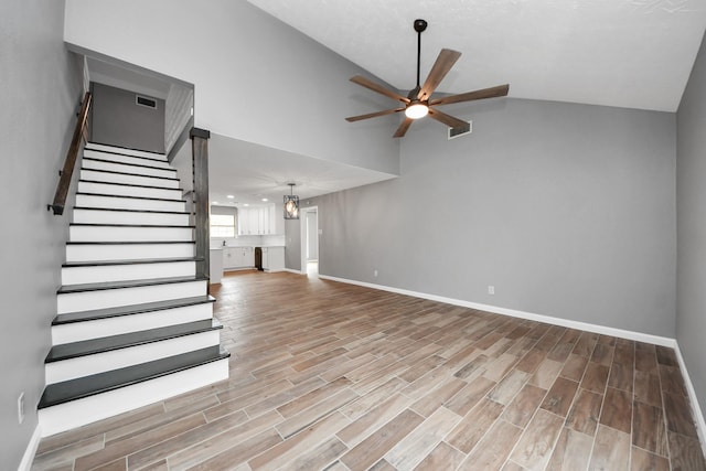 unfurnished living room featuring visible vents, lofted ceiling, baseboards, stairway, and a ceiling fan