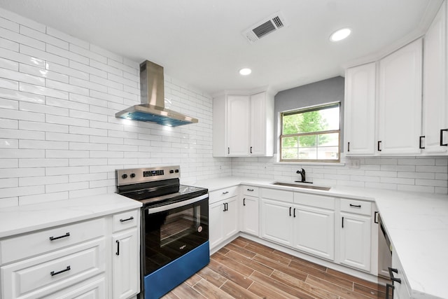 kitchen featuring wall chimney range hood, electric range, a sink, tasteful backsplash, and visible vents
