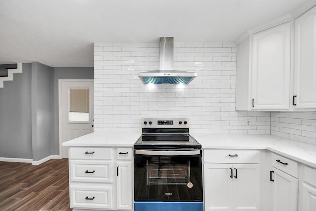 kitchen with wall chimney range hood, dark wood finished floors, baseboards, decorative backsplash, and stainless steel electric stove