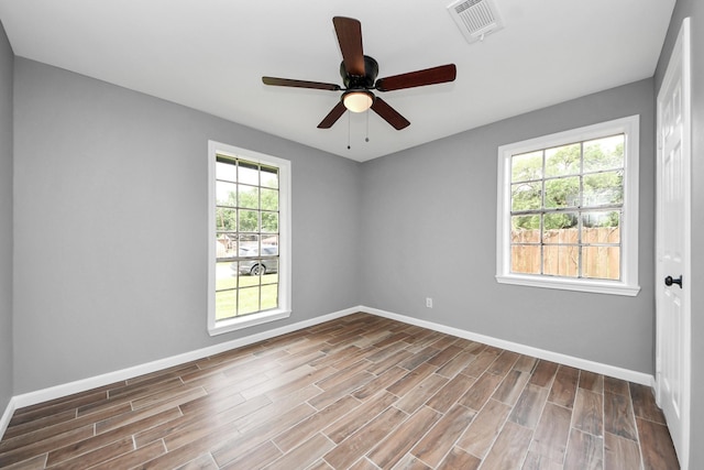 spare room featuring baseboards, ceiling fan, wood finished floors, and visible vents
