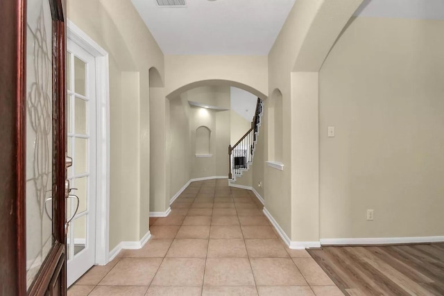 6315 Bain Dr, Missouri City, TX 77459 - hallway with visible vents, light tile patterned flooring, baseboards, stairway, and arched walkways