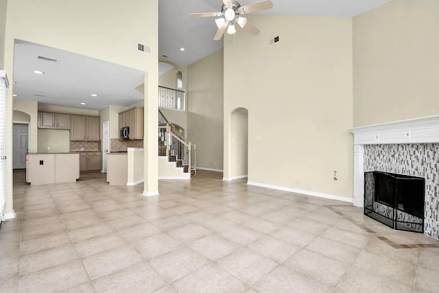 6315 Bain Dr, Missouri City, TX 77459 - unfurnished living room featuring visible vents, a high ceiling, arched walkways, a tile fireplace, and a ceiling fan