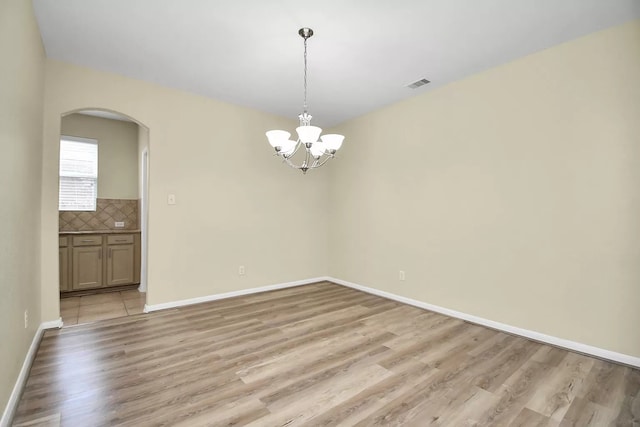 6315 Bain Dr, Missouri City, TX 77459 - empty room featuring an inviting chandelier, arched walkways, light wood-style flooring, baseboards, and visible vents