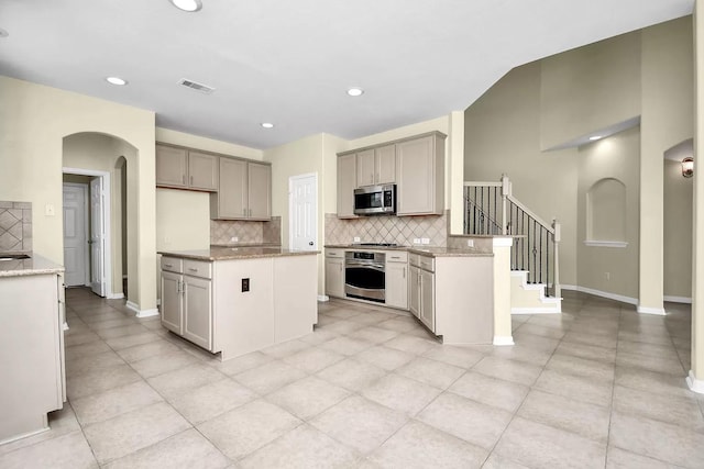 6315 Bain Dr, Missouri City, TX 77459 - kitchen featuring light stone counters, arched walkways, decorative backsplash, and appliances with stainless steel finishes