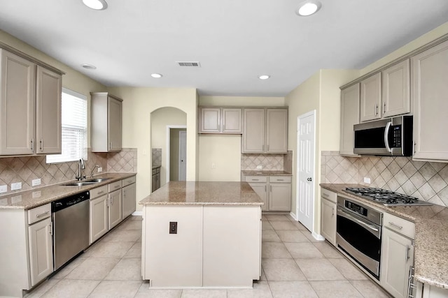 6315 Bain Dr, Missouri City, TX 77459 - kitchen with backsplash, arched walkways, a center island, a sink, and stainless steel appliances