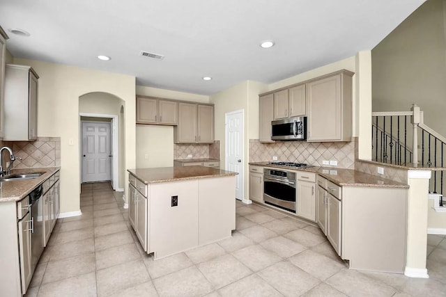 6315 Bain Dr, Missouri City, TX 77459 - kitchen featuring light stone counters, a sink, arched walkways, stainless steel appliances, and tasteful backsplash