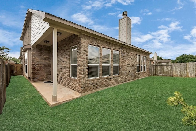 6315 Bain Dr, Missouri City, TX 77459 - back of house with brick siding, a fenced backyard, a chimney, a patio, and a yard