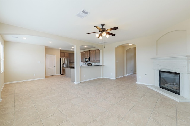 unfurnished living room with visible vents, a glass covered fireplace, light tile patterned flooring, recessed lighting, and a ceiling fan
