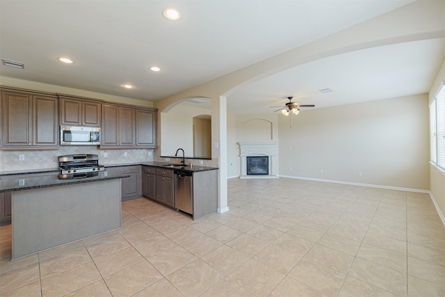 kitchen with appliances with stainless steel finishes, arched walkways, a ceiling fan, tasteful backsplash, and visible vents