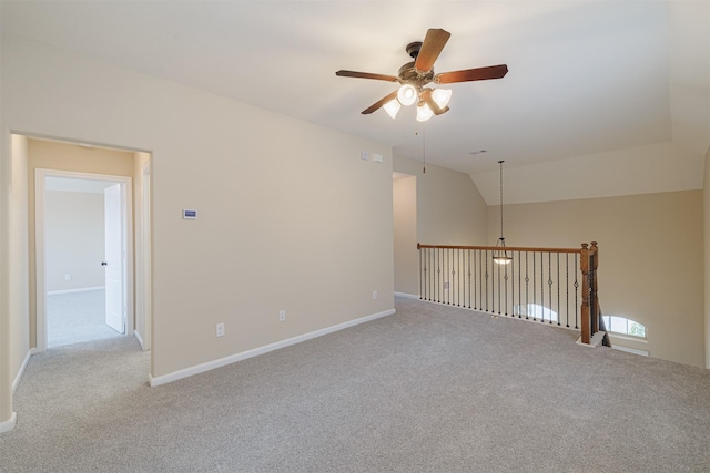 empty room featuring carpet flooring, a ceiling fan, baseboards, and vaulted ceiling
