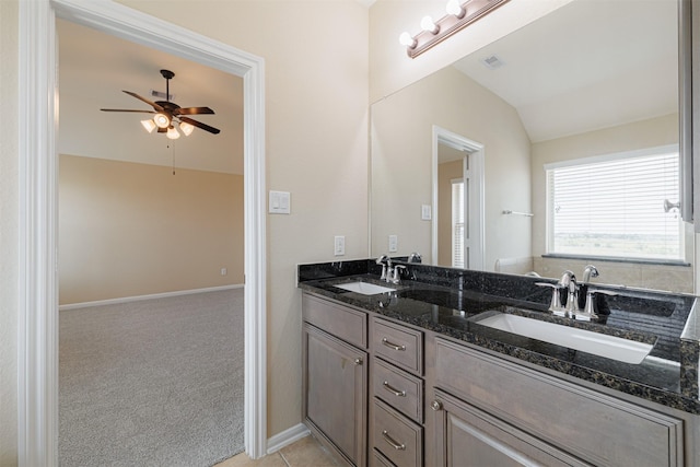 bathroom with a sink, ceiling fan, vaulted ceiling, and double vanity