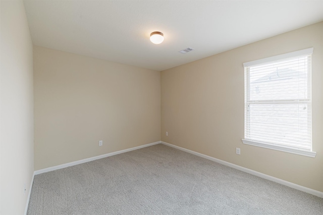 carpeted spare room featuring baseboards and visible vents