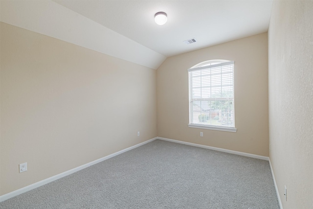 spare room featuring visible vents, carpet flooring, baseboards, and vaulted ceiling