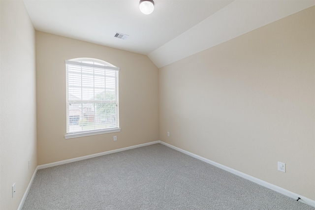 empty room featuring carpet floors, baseboards, visible vents, and lofted ceiling