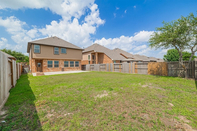 rear view of property with brick siding, a patio, a yard, and a fenced backyard