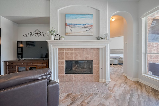 26210 Seminole Hill Ln, Katy, TX 77494 - living room featuring wood finished floors, arched walkways, a tile fireplace, and baseboards