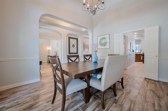 26210 Seminole Hill Ln, Katy, TX 77494 - dining room with arched walkways, light wood-style floors, a chandelier, baseboards, and a towering ceiling