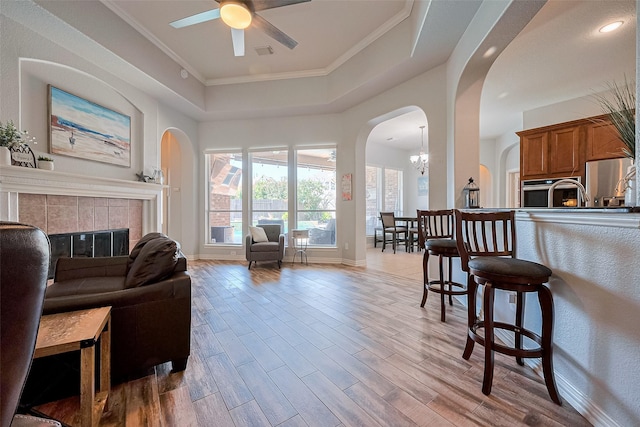 26210 Seminole Hill Ln, Katy, TX 77494 - living area featuring arched walkways, ceiling fan, a raised ceiling, a tile fireplace, and wood finished floors