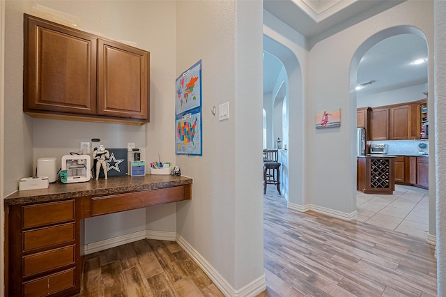 26210 Seminole Hill Ln, Katy, TX 77494 - bar featuring built in desk, arched walkways, light wood-type flooring, and baseboards
