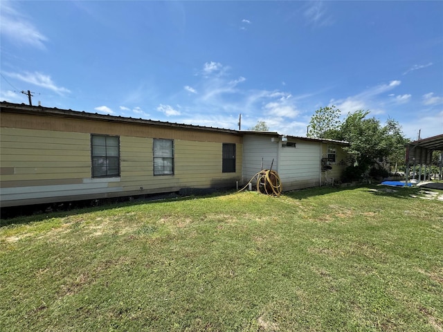 back of house featuring a lawn and a carport