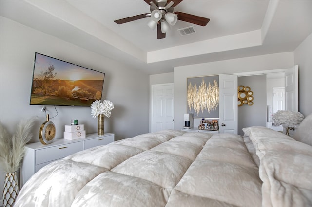 bedroom with a ceiling fan, visible vents, and a raised ceiling