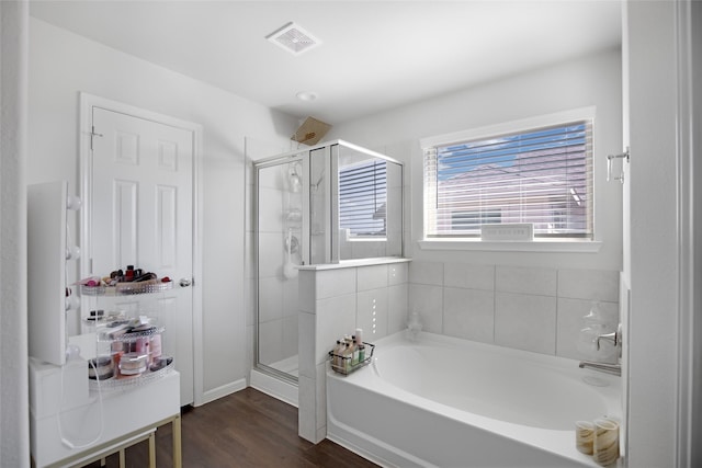 bathroom featuring wood finished floors, a stall shower, a garden tub, and visible vents