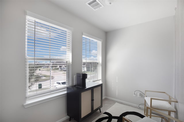 office space featuring baseboards, visible vents, and light carpet