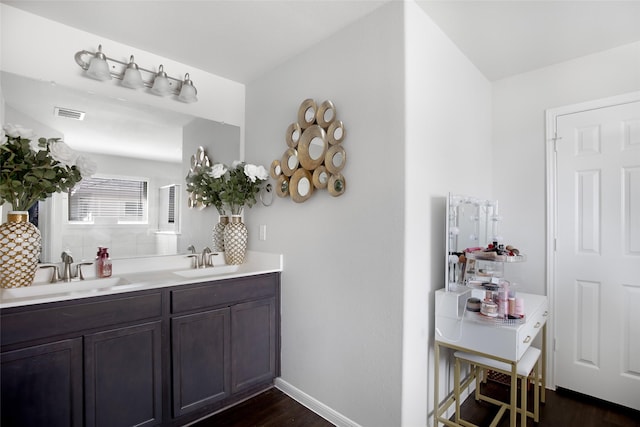 bathroom featuring visible vents, a sink, wood finished floors, and double vanity