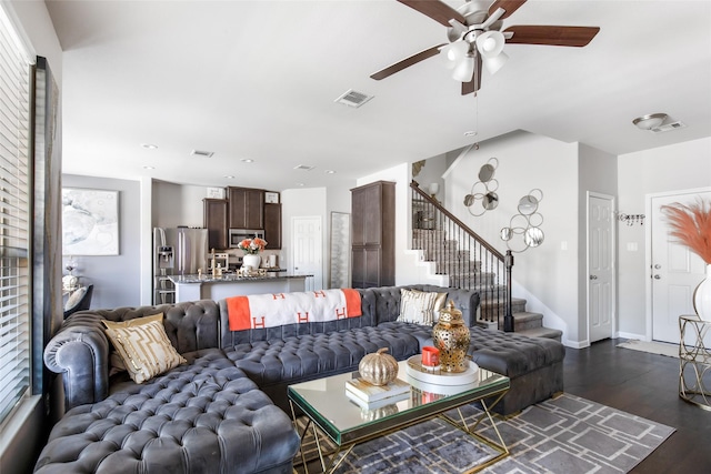 living area with stairs, a ceiling fan, visible vents, and dark wood-style flooring
