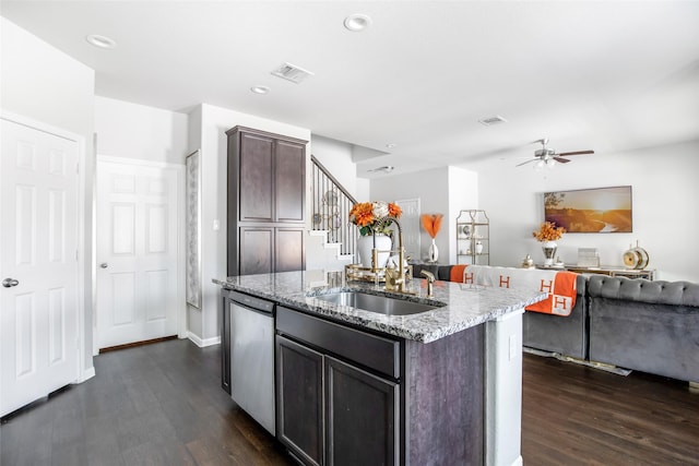 kitchen with stainless steel dishwasher, an island with sink, dark wood-style floors, light stone counters, and a sink