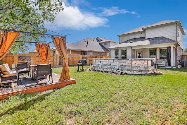 rear view of property featuring a lawn, a fenced backyard, a swimming pool, and a deck
